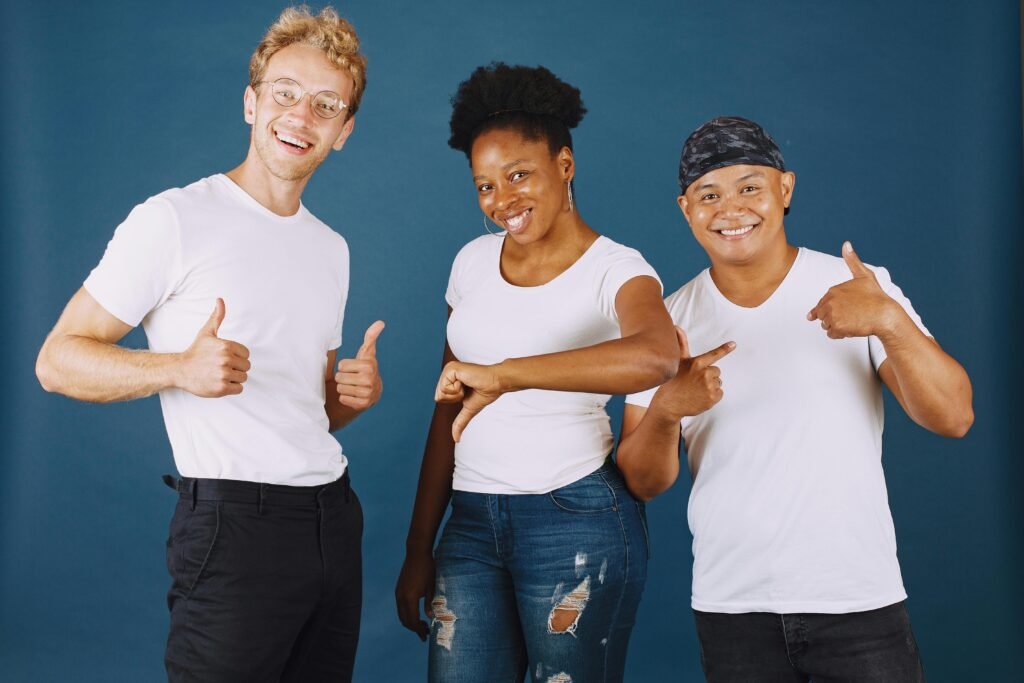 Three friends of diverse backgrounds posing happily in a studio setting with a blue backdrop.