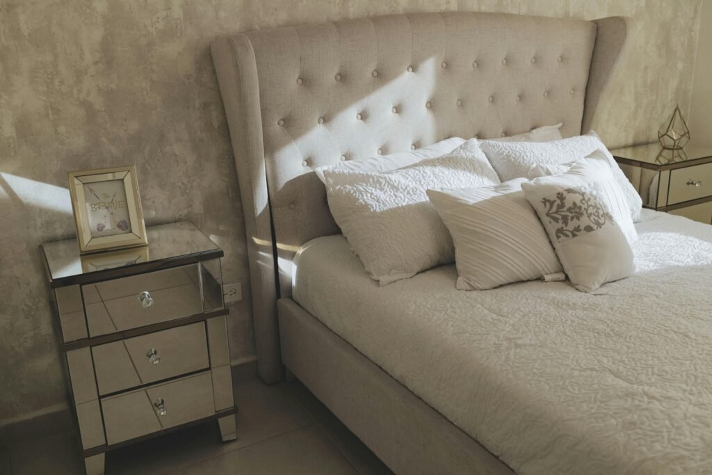 Cozy bedroom with stylish headboard, pillows, and mirrored side tables.