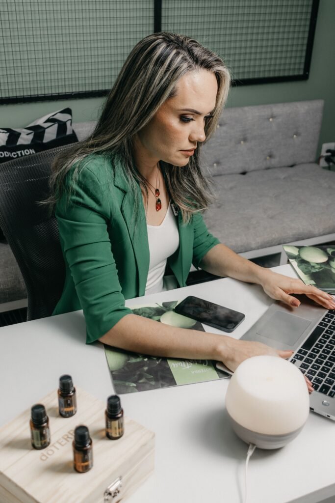 Businesswoman in green blazer focused on work with laptop at office desk.