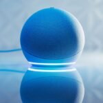 A smart speaker with glowing blue LED lighting and its reflection on a surface.