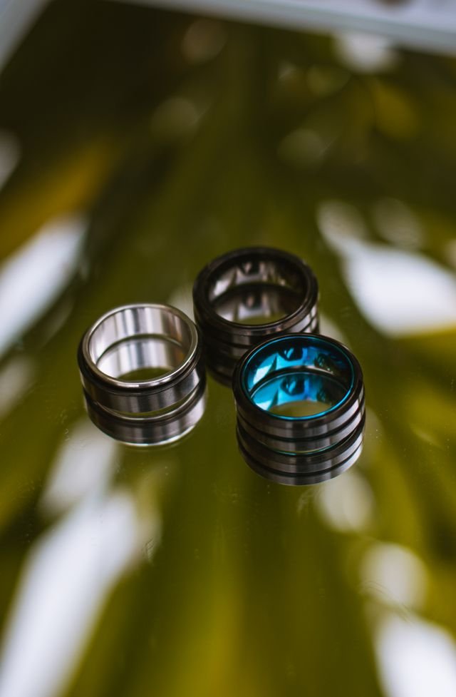 Three stylish metal rings displayed on a glossy reflective surface, showcasing elegance and design.