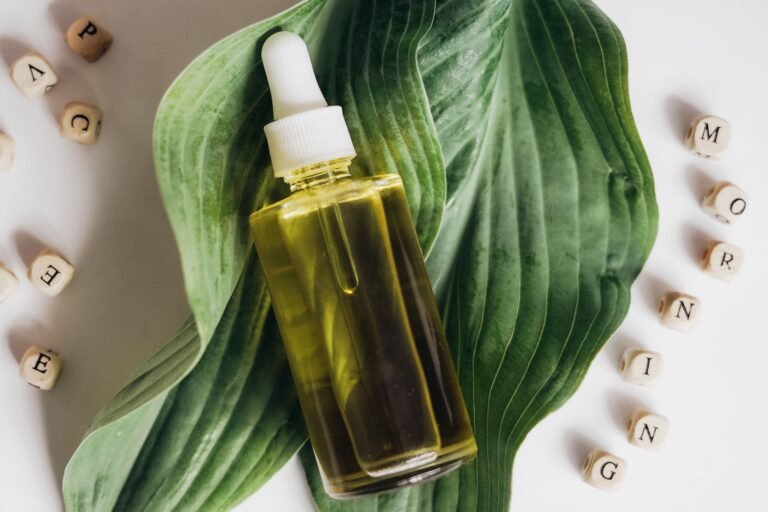 Una botella de aceite natural para el cuidado de la piel colocada sobre hojas verdes con bloques de letras que forman la palabra 'mañana'.