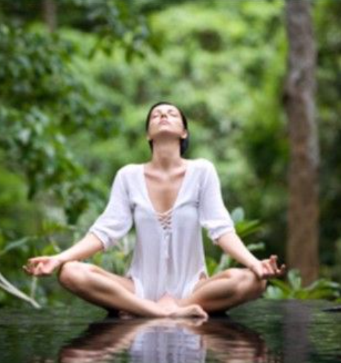 Mujer practicando una técnica de relajación y meditación en la naturaleza.
