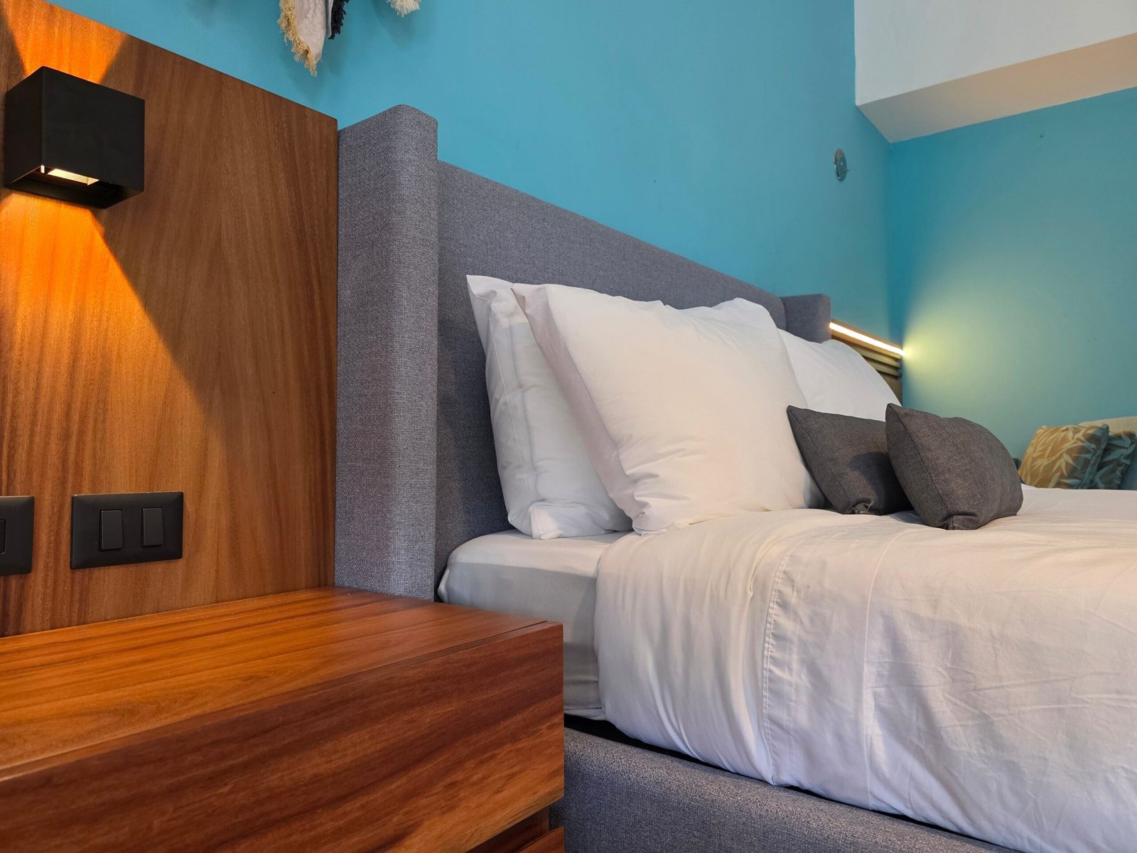Stylish modern bedroom featuring a cozy bed, wooden nightstand, and warm lighting.