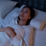 An Asian woman lying awake in bed, reflecting on her thoughts during a sleepless night.