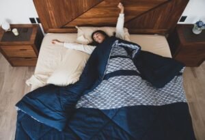 A woman stretches and relaxes in a cozy bedroom setting, creating a serene morning ambiance.